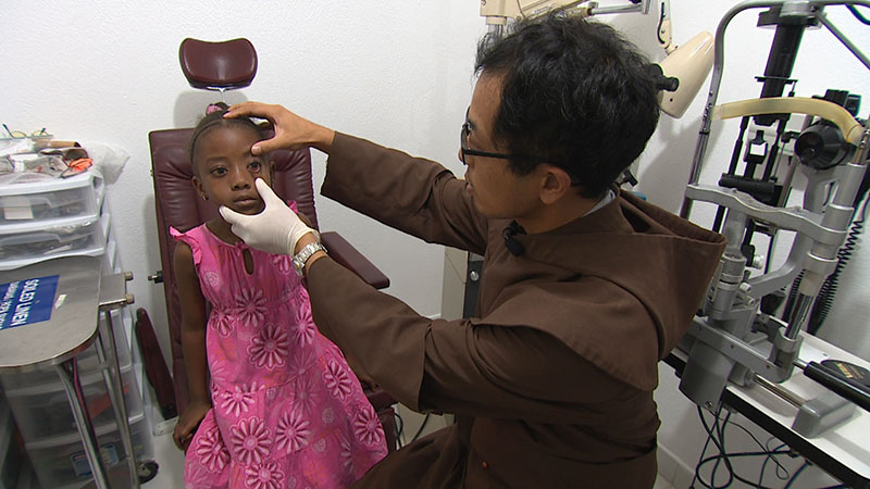 Brother James Kim conducts an eye exam on a young girl.