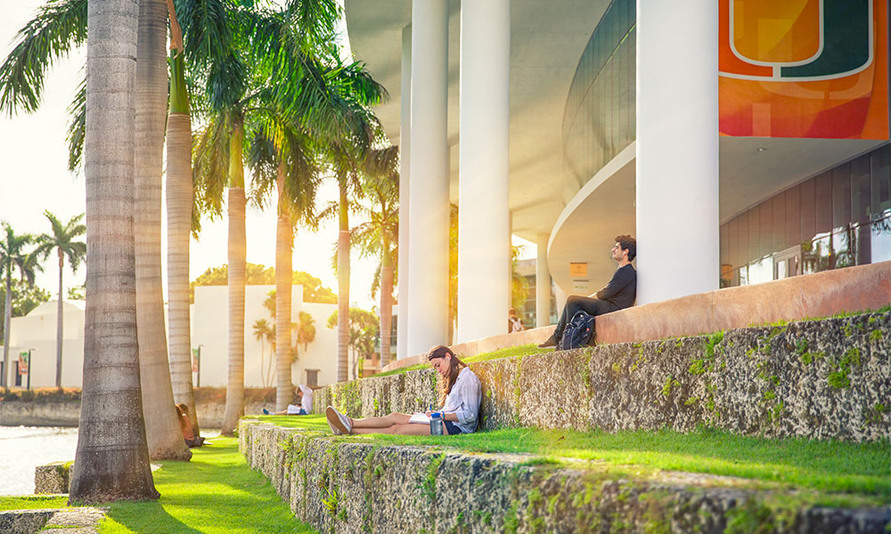 Students relax lakeside in front of the student center