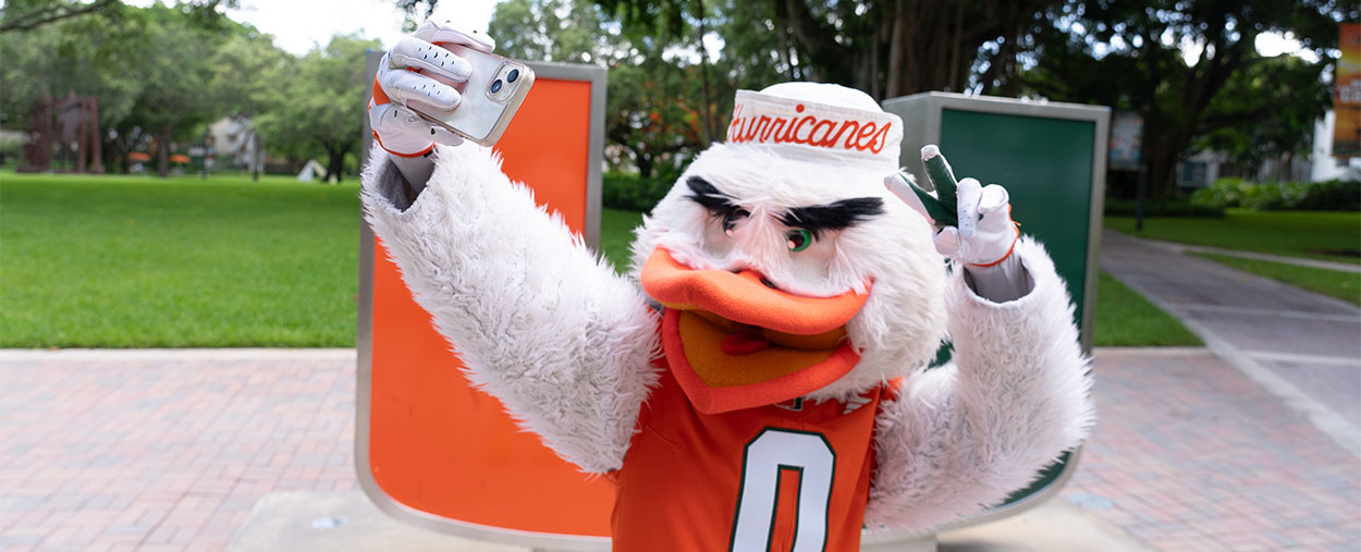 Sebastian the Ibis taking a selfie in front of the U statue