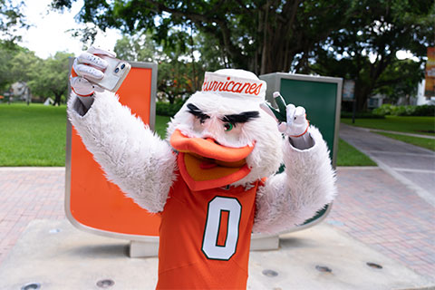 Sebastian the Ibis taking a selfie in front of the U statue